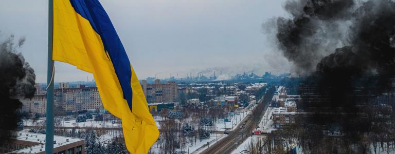 View of Ukraine flag by bombing site in a city in winter.